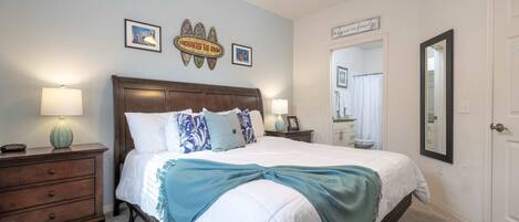 A bedroom with a bed, two bedside tables, a nightstand, a mirror, and a ceiling fan.