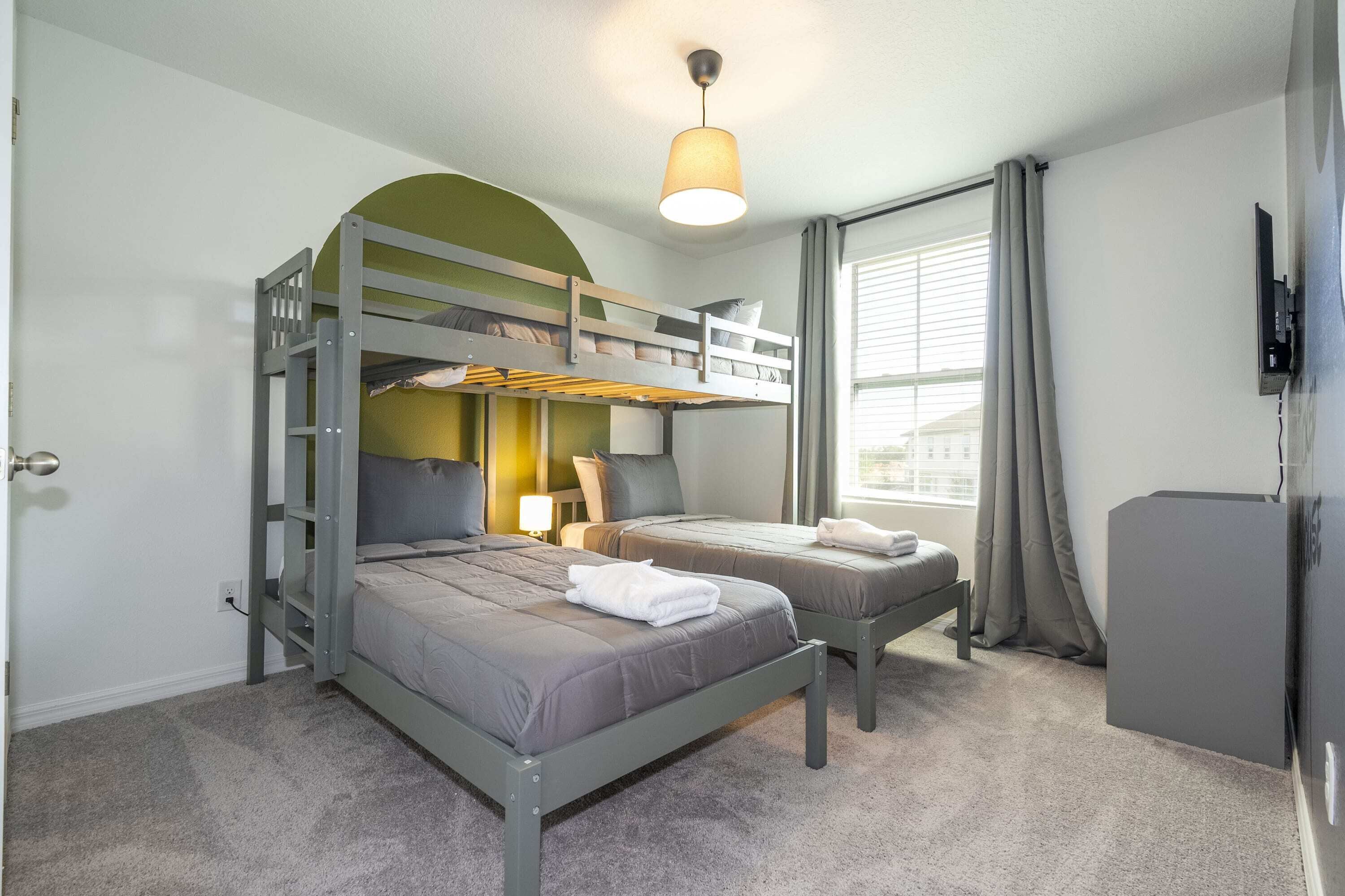 A room with bunk beds, a desk, and a window with curtains.