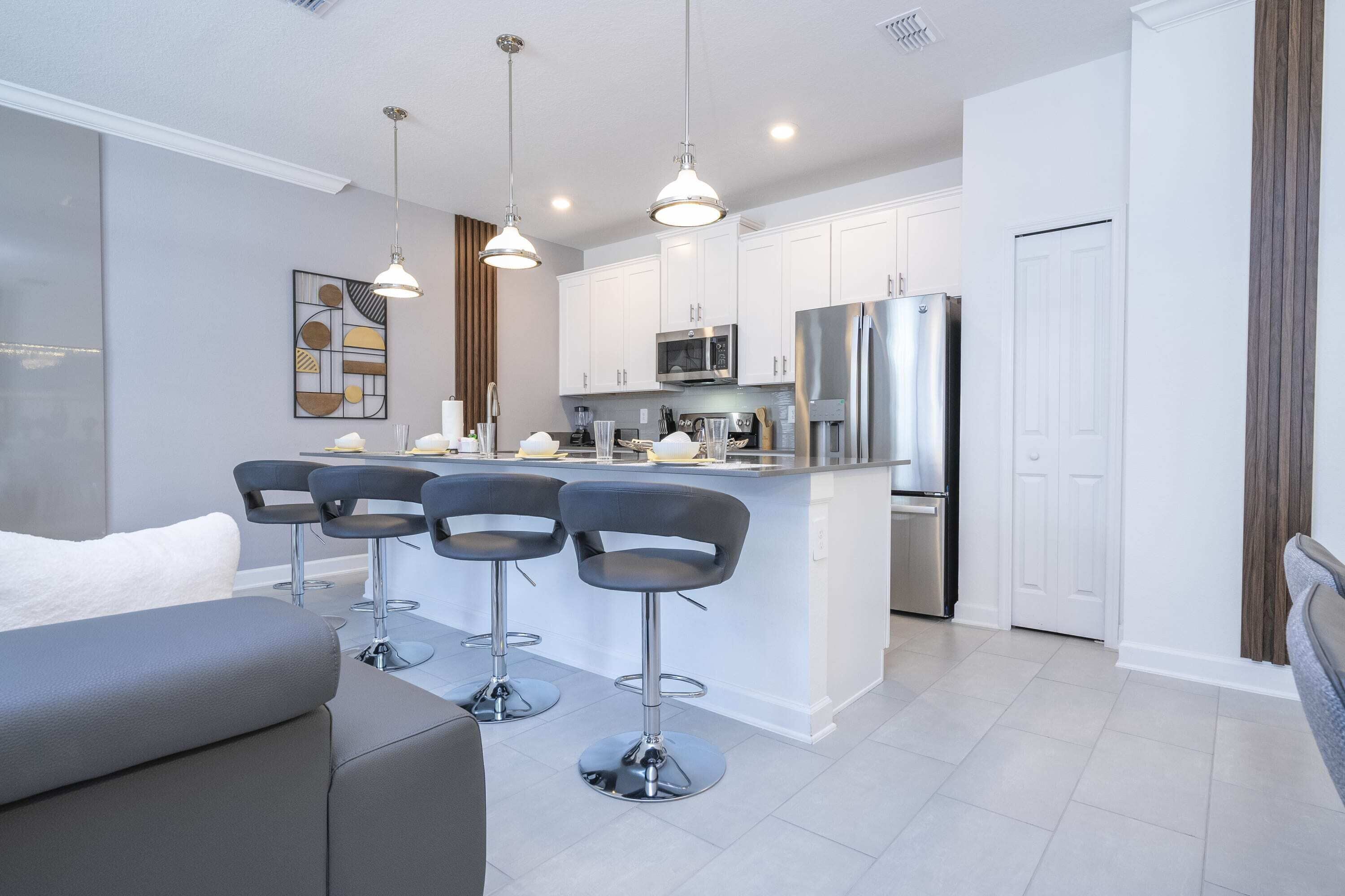 A modern kitchen with white cabinets, stainless steel appliances, and a central island with bar stools.