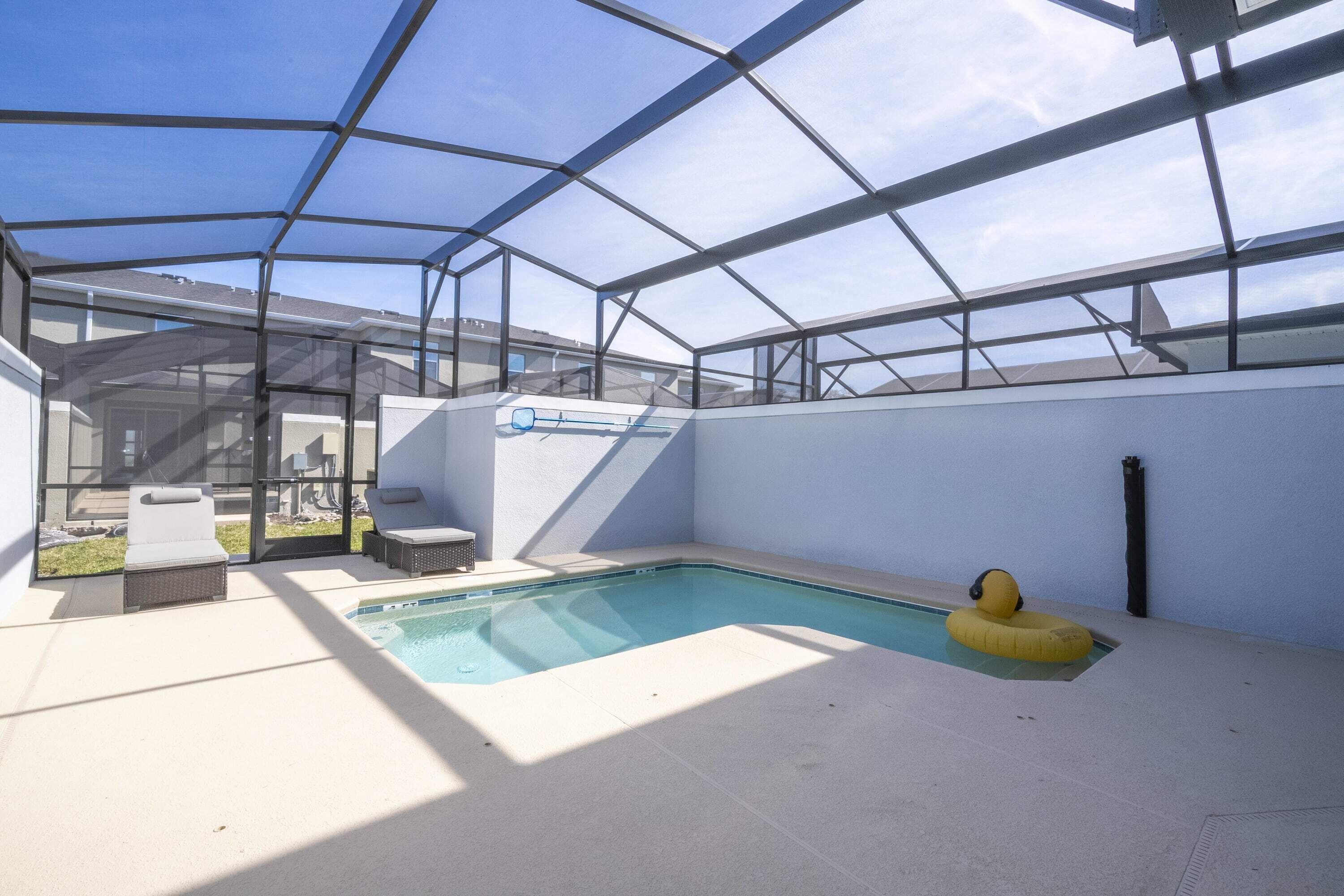 An indoor swimming pool with a glass ceiling, a yellow inflatable ring, and a lounge area with chairs and a table.
