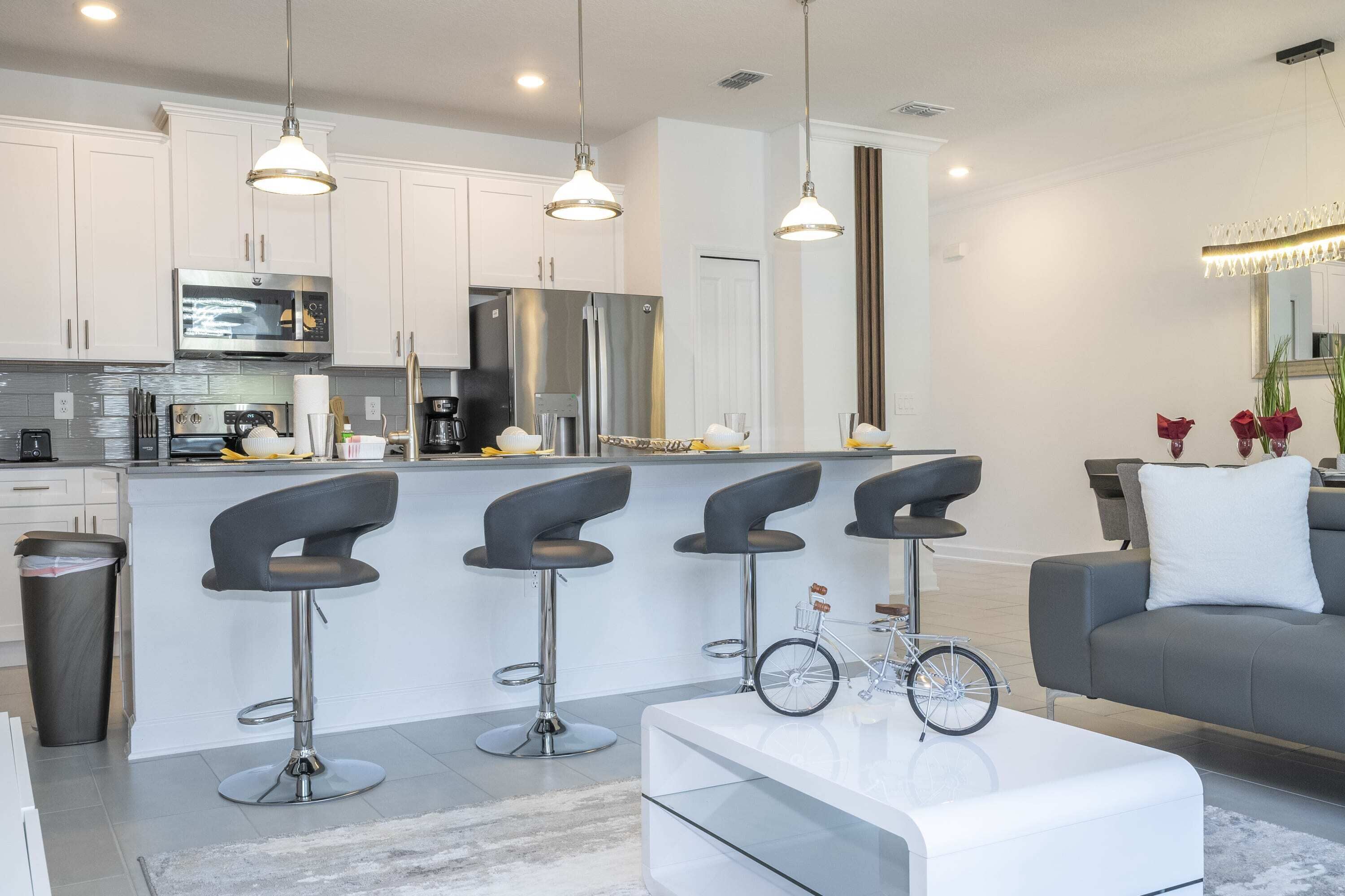 A modern kitchen with white cabinets, stainless steel appliances, and a central island with bar stools.