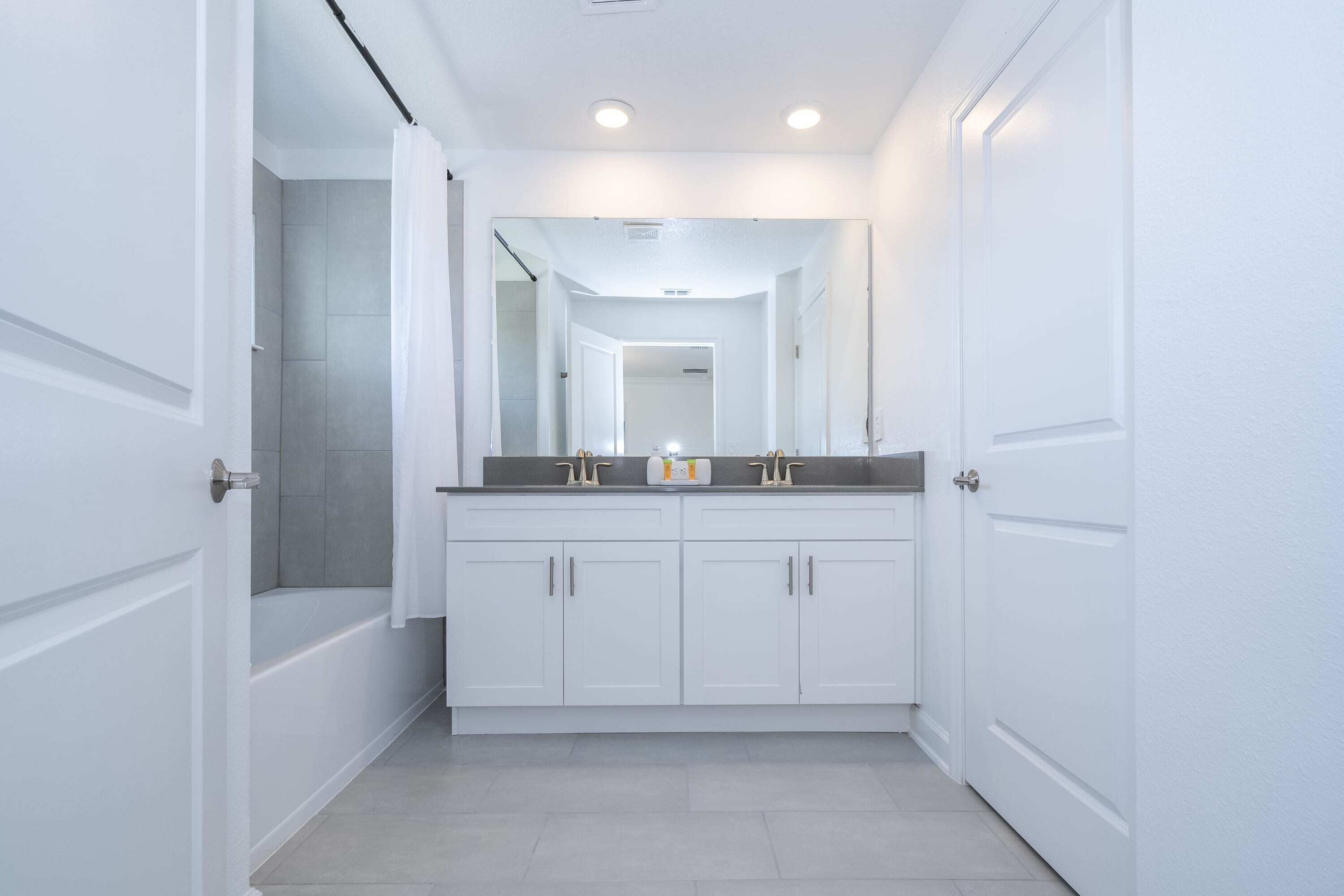 A modern bathroom with a double vanity, a shower, and a mirror above the sink.