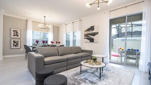 A modern living room with a grey sofa, round ottomans, a coffee table, and a large window with a view of the outside.