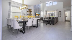 A spacious dining area with a modern chandelier, a large window, and a view of the outdoors.