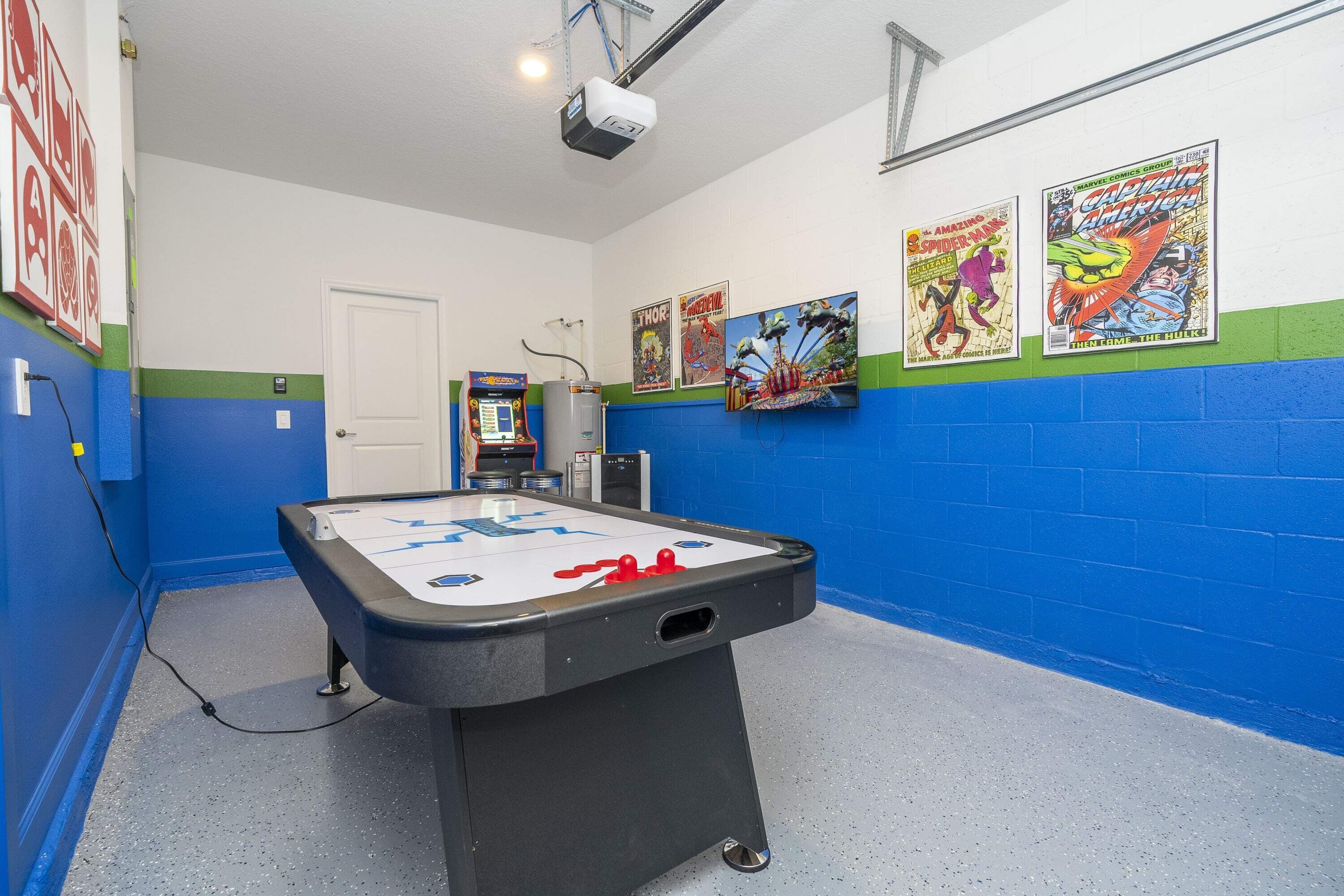 Una habitación con mesa de billar, proyector y carteles de cómics en la pared.