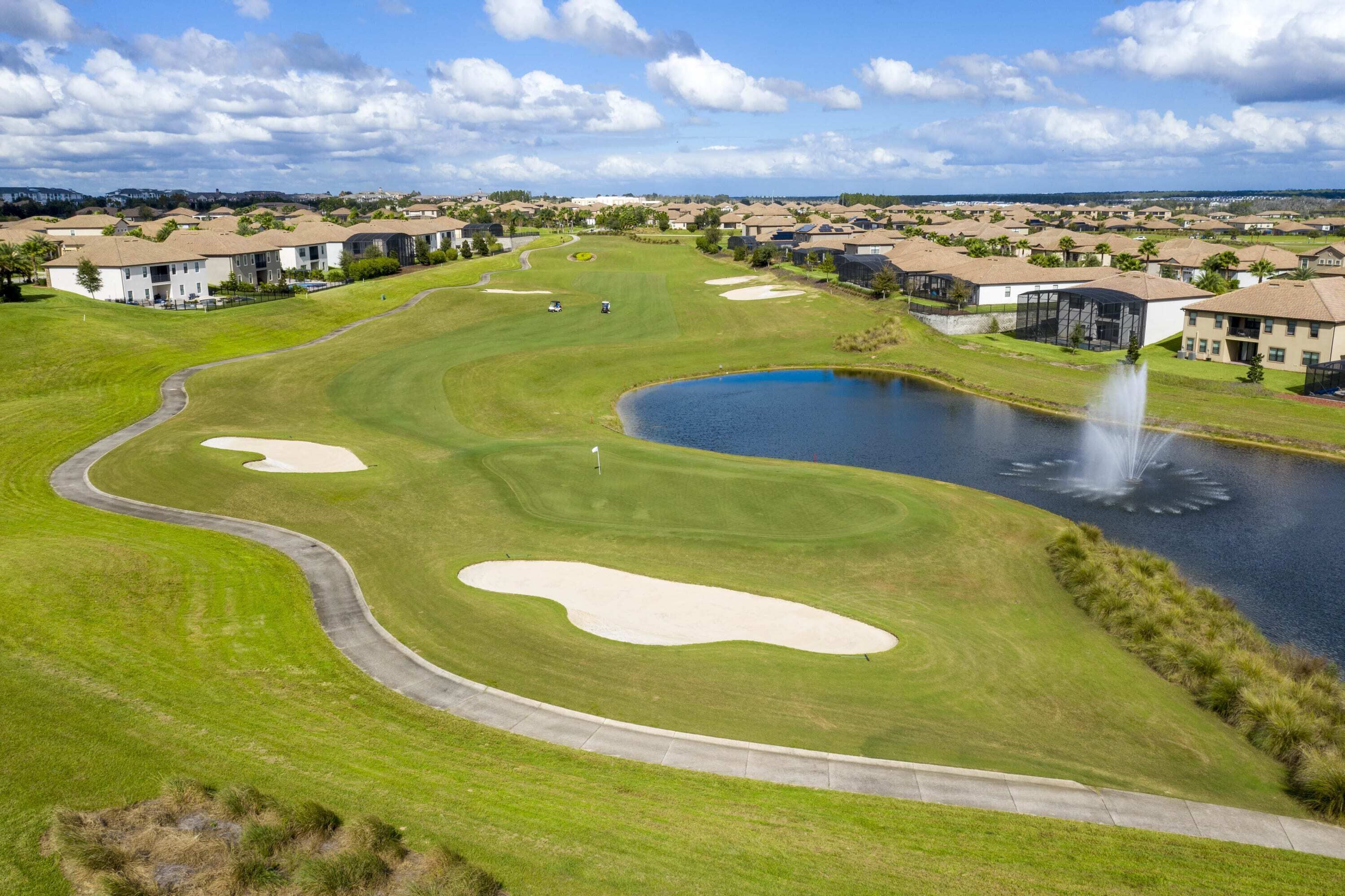 Een golfbaan met bunkers, een vijver en een fontein.
