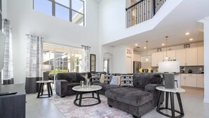 A spacious living room with a grey sectional sofa, two round coffee tables, and a large window.