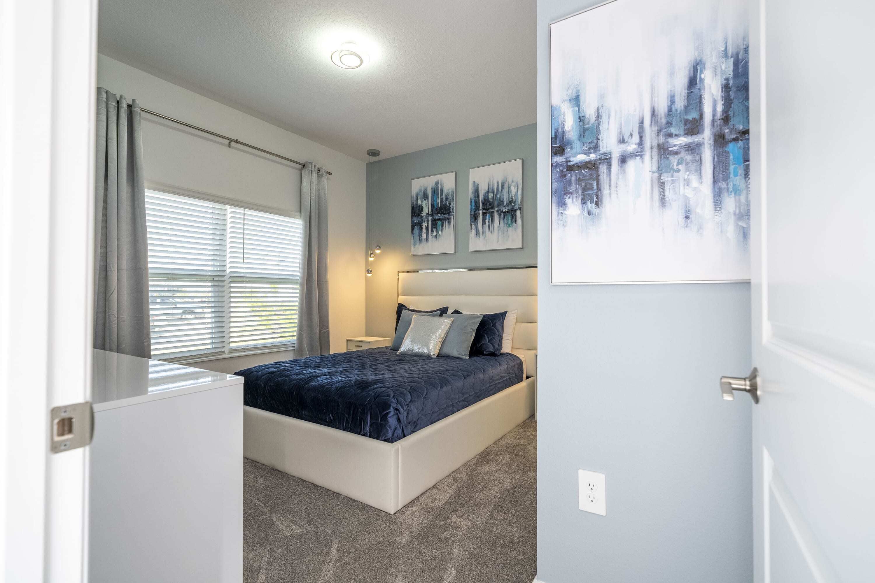 A bedroom with a bed, a nightstand, and a wall-mounted light.