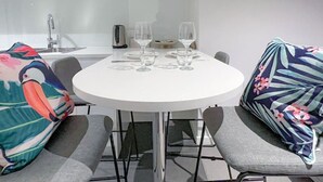 A round dining table with four chairs, a white countertop, and a toaster. - Skytower Escape:Modern 2B Apt (Brisbane City)