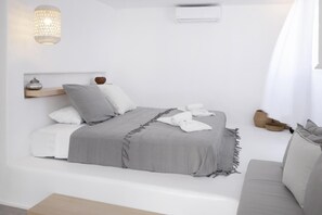 Ein schlicht eingerichtetes Schlafzimmer mit Bett, Nachttisch und Pendelleuchte.