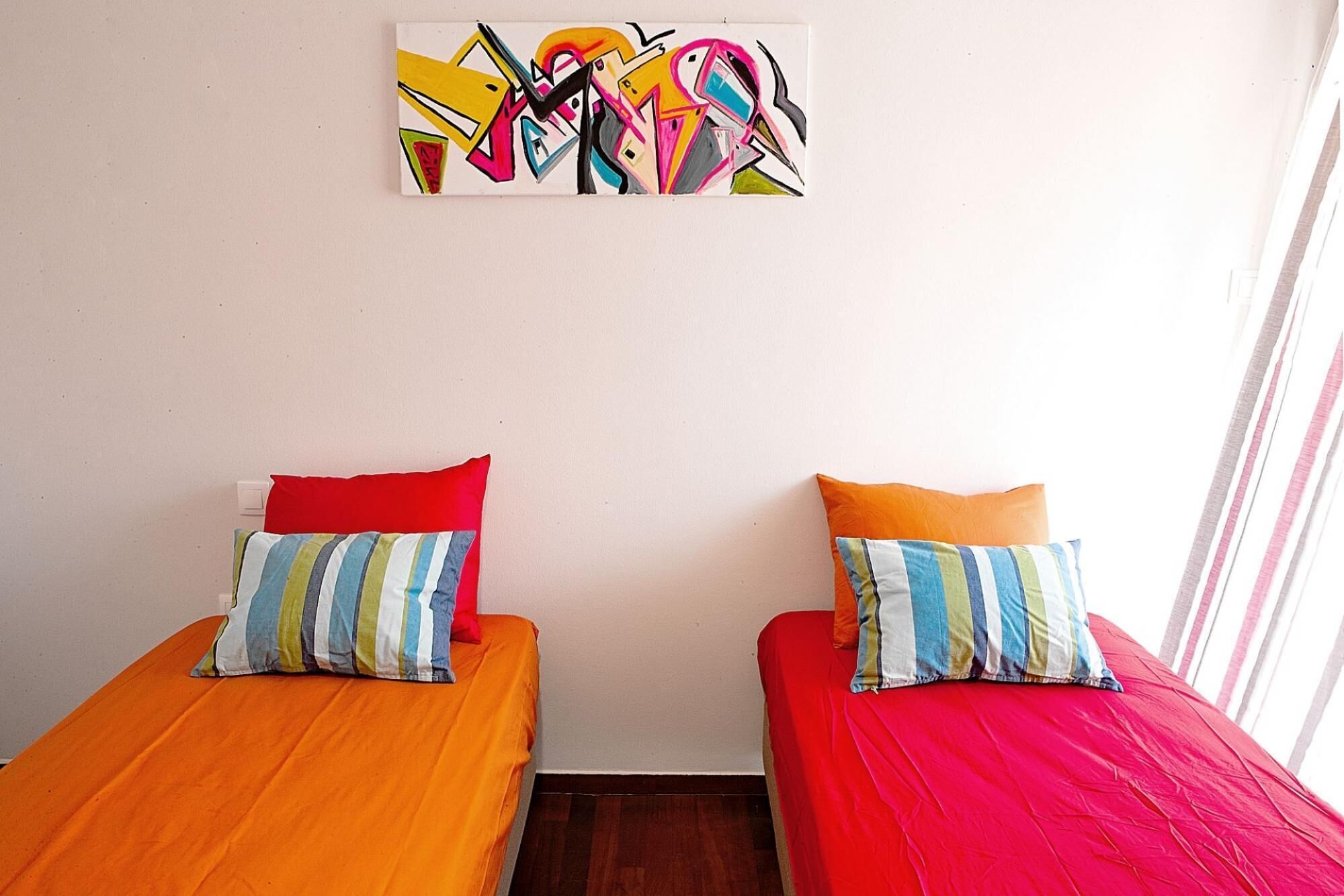 A room with two beds, each with a colorful striped pillow.