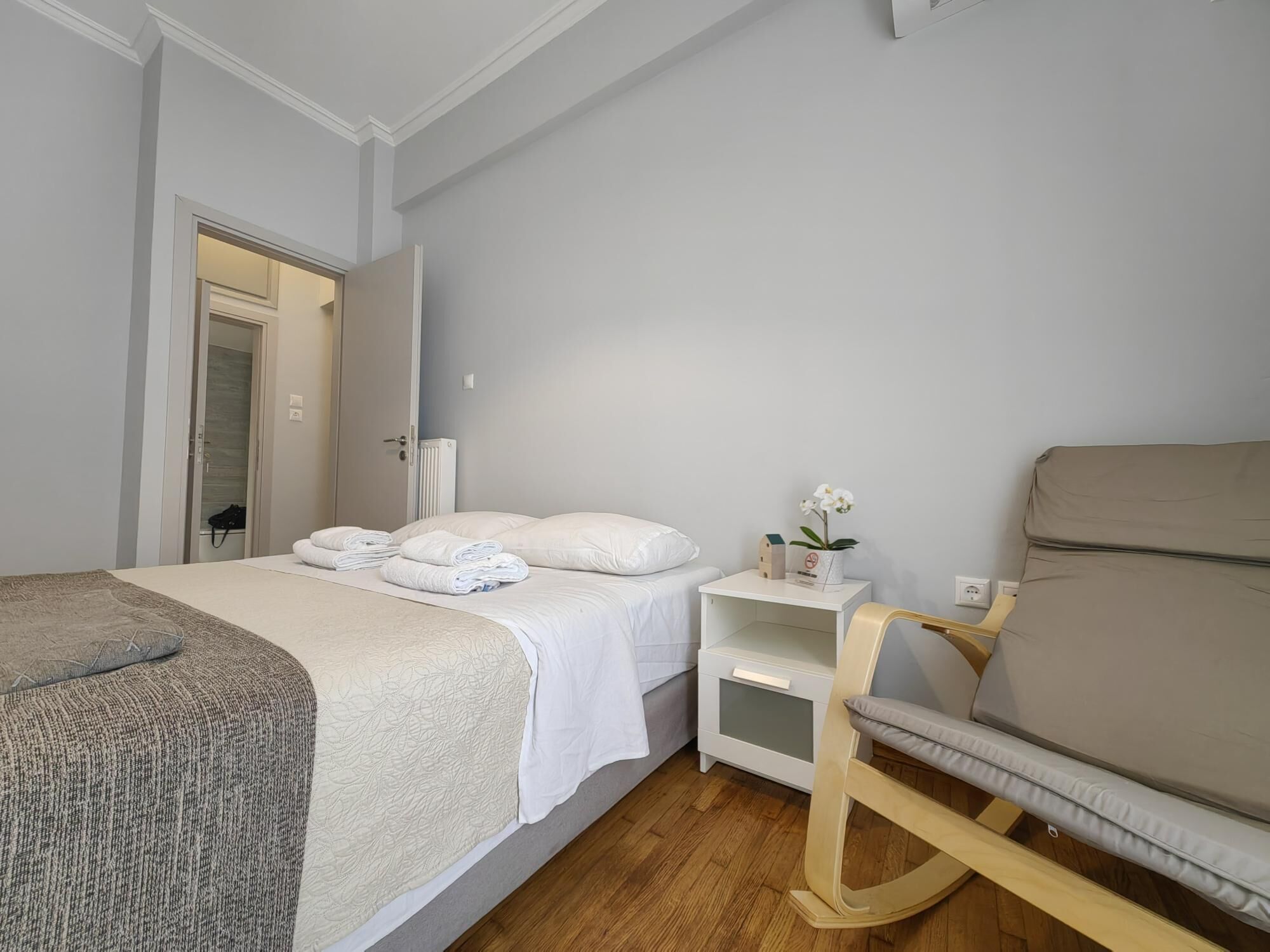 Ein Schlafzimmer mit Bett, Nachttisch, Sessel und Heizkörper.