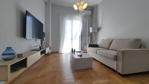 Una sala de estar moderna con un televisor de pantalla plana, un sofá, una mesita de centro y una lámpara.
