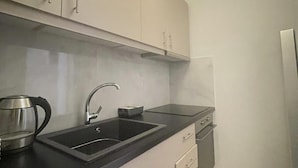 Una cocina moderna con encimera negra, electrodomésticos de acero inoxidable y armarios de colores claros.
