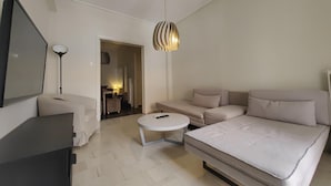A modern, minimalist bedroom with a large bed, a sofa, a desk, and a TV. - Demetra - Koukaki Center Apartment (Athens)