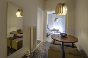 Un couloir d’hôtel moderne avec une table ronde, un miroir et un radiateur.
