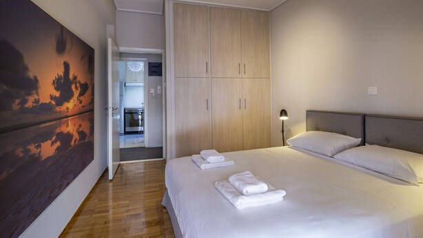 A hotel room with a large bed, a wardrobe, and a painting on the wall. - Demetra - Koukaki Center Apartment (Athens)