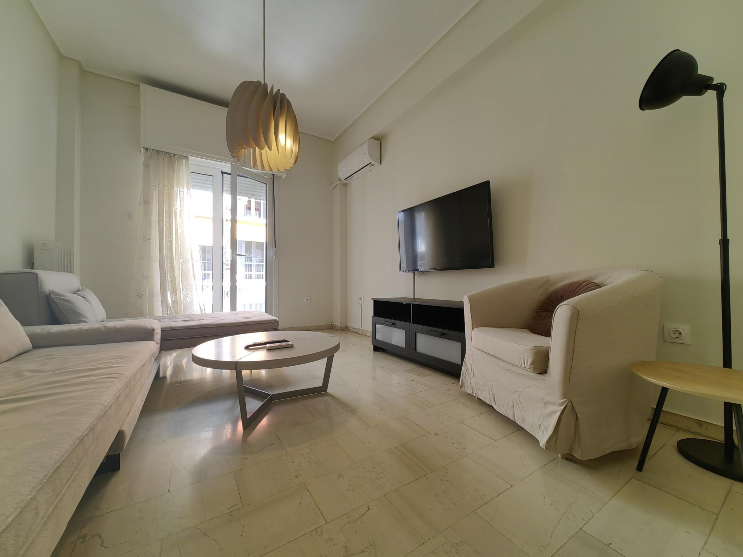 A modern living room with a sofa, a coffee table, a TV, and a lamp.