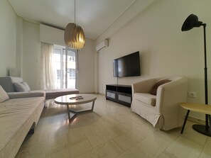 Un salon moderne avec un canapé, une table basse, un téléviseur et une lampe.