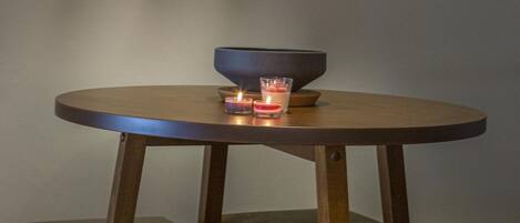 A round table with a dark bowl and two lit candles, surrounded by cushioned seating.