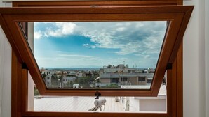 A skylight with a view of a cityscape, including buildings and a distant mountain range. - Leo - Unique Glyfada Apartment (Glyfada)