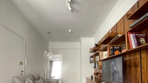 A modern living room with a grey sofa, a wooden entertainment unit, and a television.