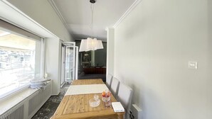 A hotel room with a wooden dining table, a glass of water, and a white lamp.