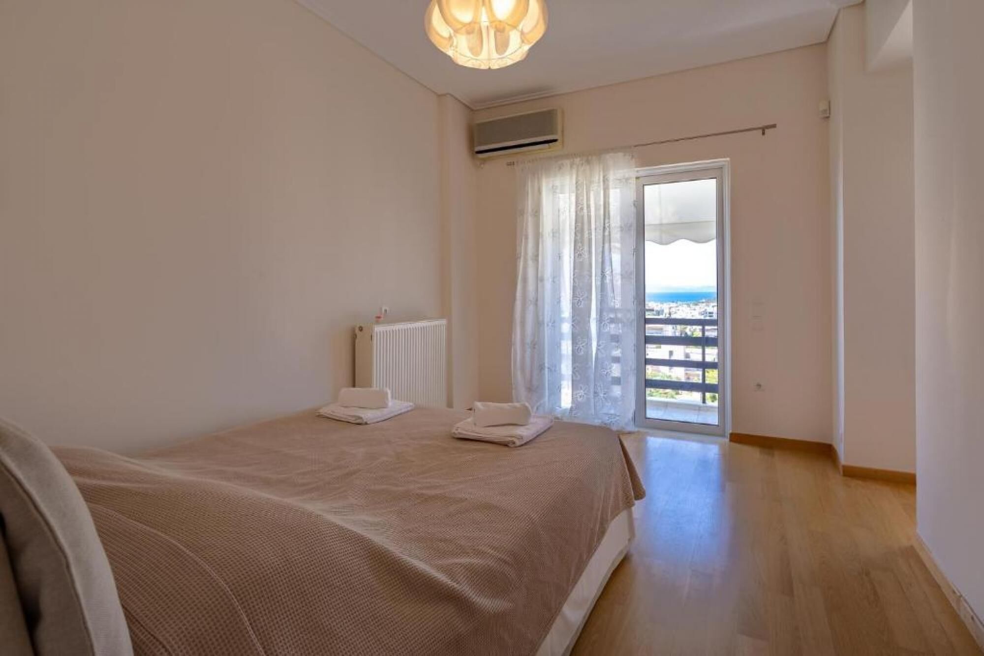 A bedroom with a bed, a radiator, and a view of the outside.