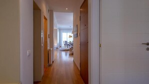 Un couloir au plancher de bois menant à une salle à manger avec une table et des chaises.