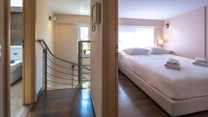 A hotel room with a bed, a bathroom, and a staircase. - Solon - Deluxe City Center Apartment (Agios Dimitrios)