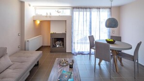 A modern living room with a sofa, coffee table, and dining area with chairs and a table. - Solon - Deluxe City Center Apartment (Agios Dimitrios)