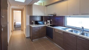 A modern kitchen with dark wood cabinets, a built-in microwave, and a window providing natural light. - Solon - Deluxe City Center Apartment (Agios Dimitrios)