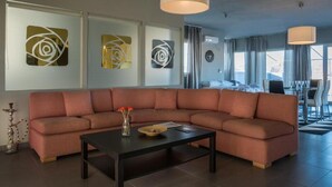 A modern living room with a large sectional sofa, a coffee table, and abstract wall art. - Virgo - Loft With Spectacular View to Acropolis (Athens)