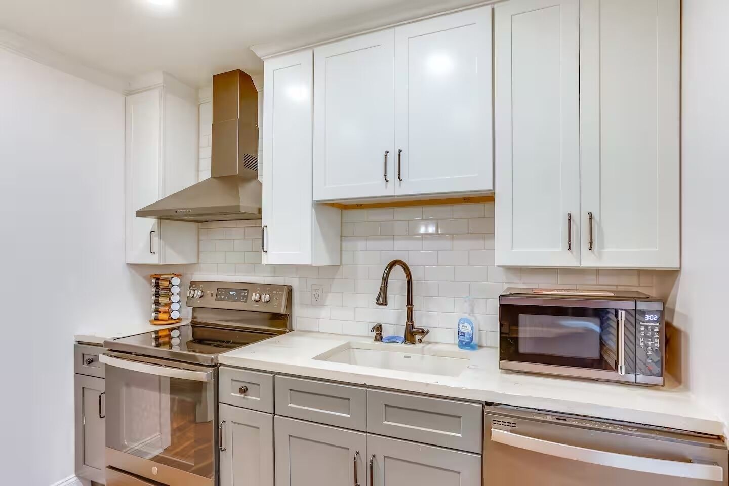 A modern kitchen with white cabinets, stainless steel appliances, and a tiled backsplash.