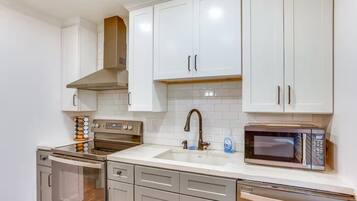 A modern kitchen with white cabinets, stainless steel appliances, and a tiled backsplash.