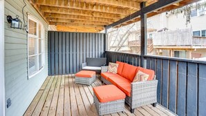Une véranda aménagée avec des meubles en osier et un téléviseur.