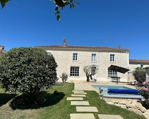 Un edificio in pietra con tetto in tegole, una piscina e un prato curato.