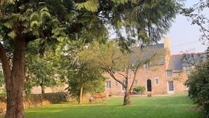 A stone building with a large lawn and trees.