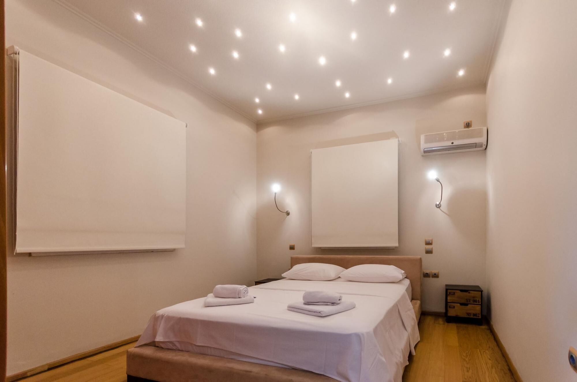 Ein Hotelzimmer mit einem Bett, Nachttischlampen, einer Deckenleuchte und einer Wand-Klimaanlage.