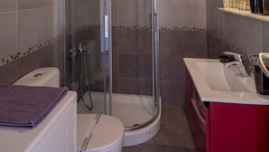 A bathroom with a glass-enclosed shower, a white toilet, and a red vanity with a sink. - Archer - Sea View Apartment (Vari-Voula-Vouliagmeni)