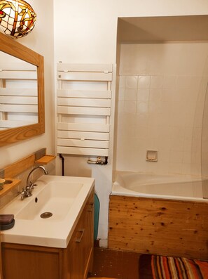 Bathroom features a sink, mirror, and bathtub with a shower curtain.