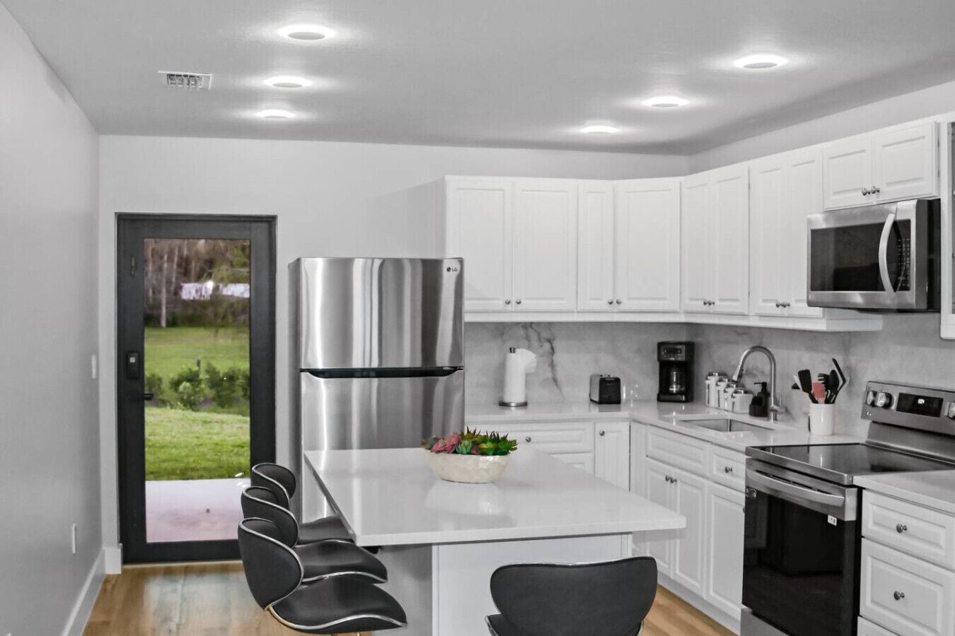 Een moderne keuken met witte kasten, roestvrijstalen apparatuur en een centraal eiland met zitplaatsen.