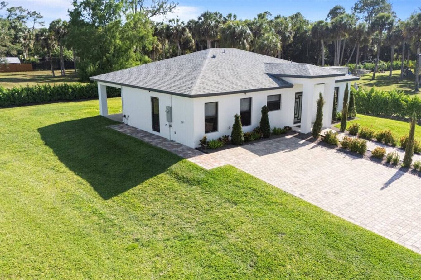 A modern two-story house with a well-maintained lawn and a paved driveway.