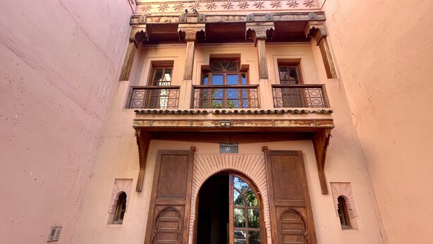 Ein Gebäude mit einem Balkon, einem großen Rundbogenportal und einem Schild mit der Aufschrift 'Pavilion B1'.