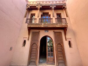 A building with a balcony, a large arched doorway, and a sign reading "Pavilion B1". - Le Temps Des Fleurs - Marrakech (Marrakech)