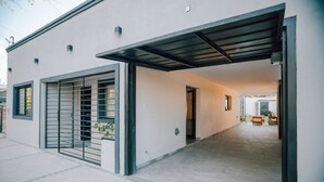 A modern building with a covered garage, a tiled walkway, and a visible door leading to an interior space. - Sumérgete en el Lujo, en una Ubicación Inigualable. ¡Tu Escape Perfecto! (San Rafael)