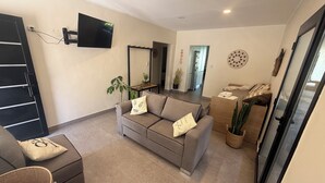 A modern living room with a grey sofa, a small table, and a TV mounted on the wall. - Sumérgete en el Lujo, en una Ubicación Inigualable. ¡Tu Escape Perfecto! (San Rafael)