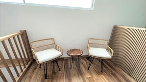 A corner room with two wicker chairs, a small round table, and a wooden floor. - Casa Hotel Real (Circasia)