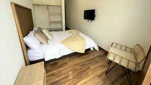 A bedroom with a bed, a chair, a TV, and a wardrobe. - Casa Hotel Real (Circasia)