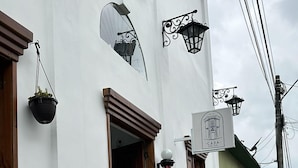A narrow street with white buildings, a barber shop sign, and hanging plants. - Casa Hotel Real (Circasia)